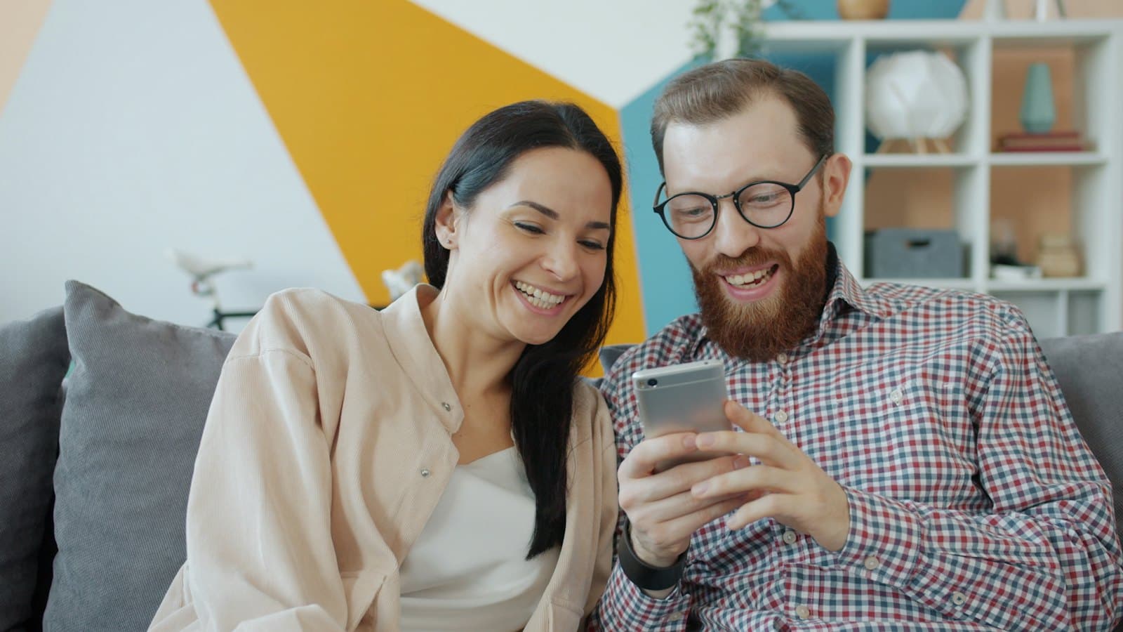Telefonuna bakıp gülümseyen bir çift