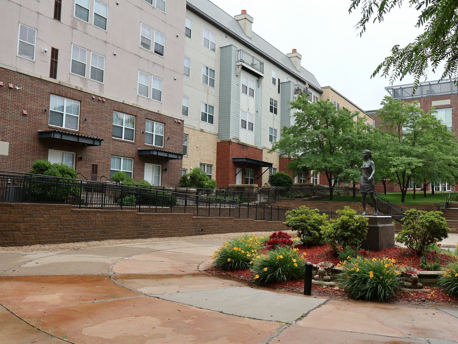 A multi-story residential building with a garden and trees